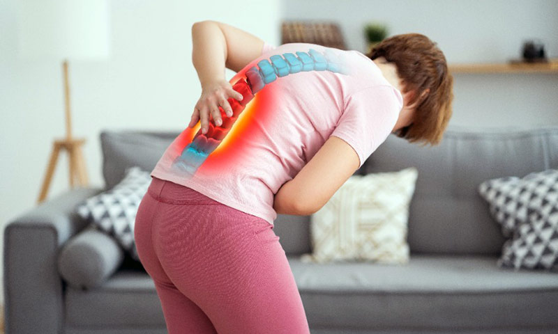 Diskusprolaps øvelser bliver lavet af dame i dagligstue. På illustrationen kan man se at hun har mange smerter i ryggen.